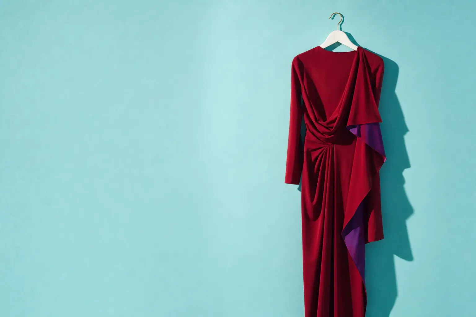 A crimson garment hanging against an aqua wall