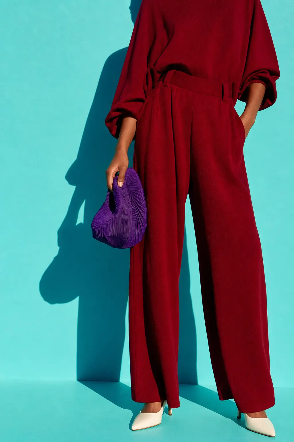A figure in crimson against a bright aqua backdrop