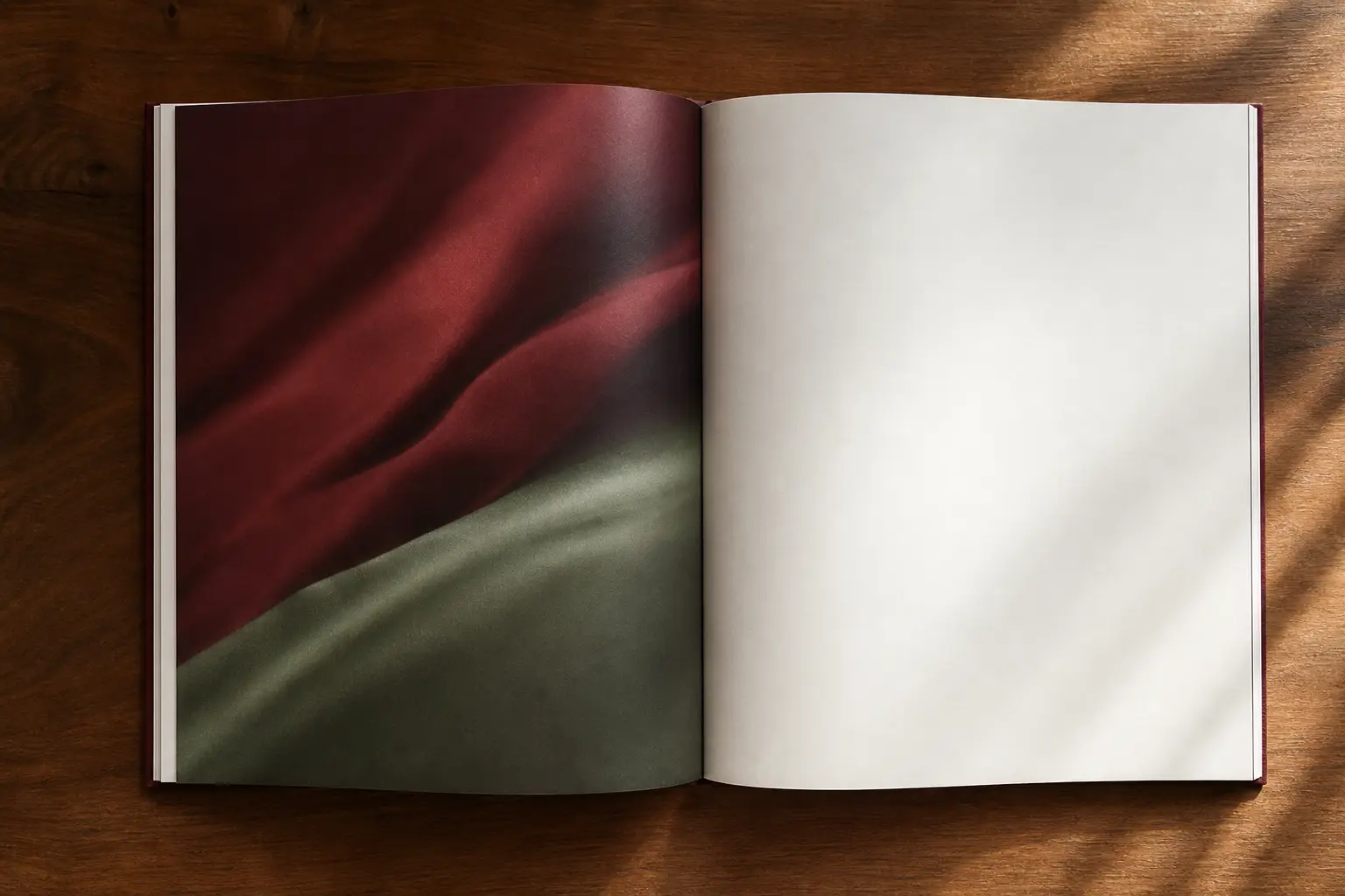 An open catalogue lying on bordeaux and sage colour blocks, the right page blank