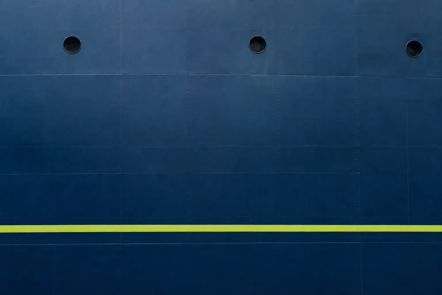 A navy painted steel hull with a lime waterline stripe