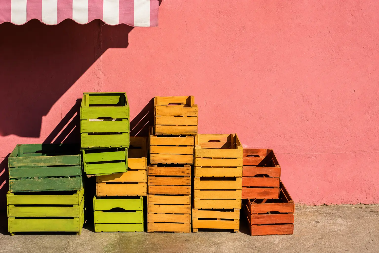 Empty stacked crates against a pink painted wall