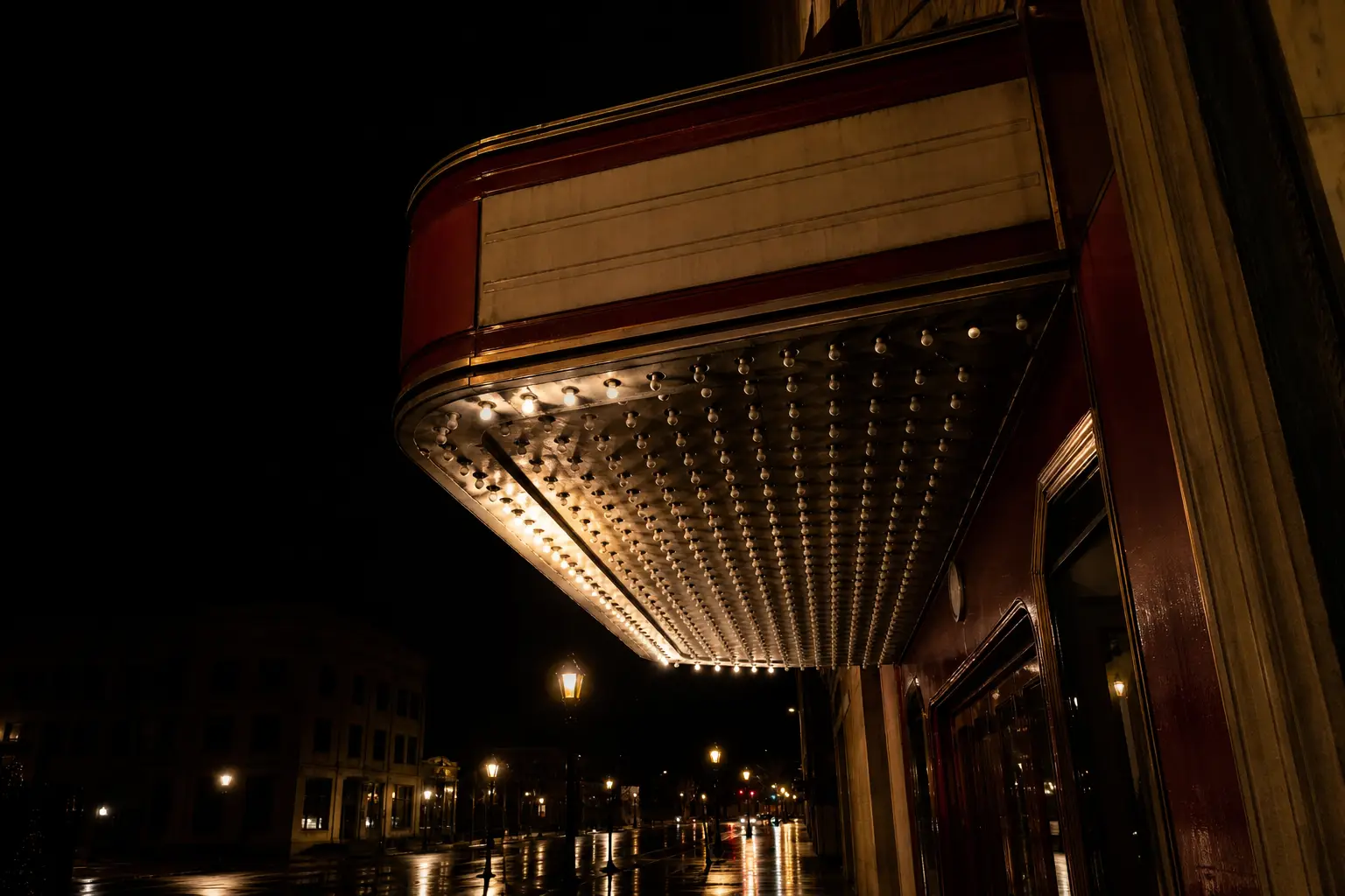Rows of unlit bulbs under a cinema canopy at night