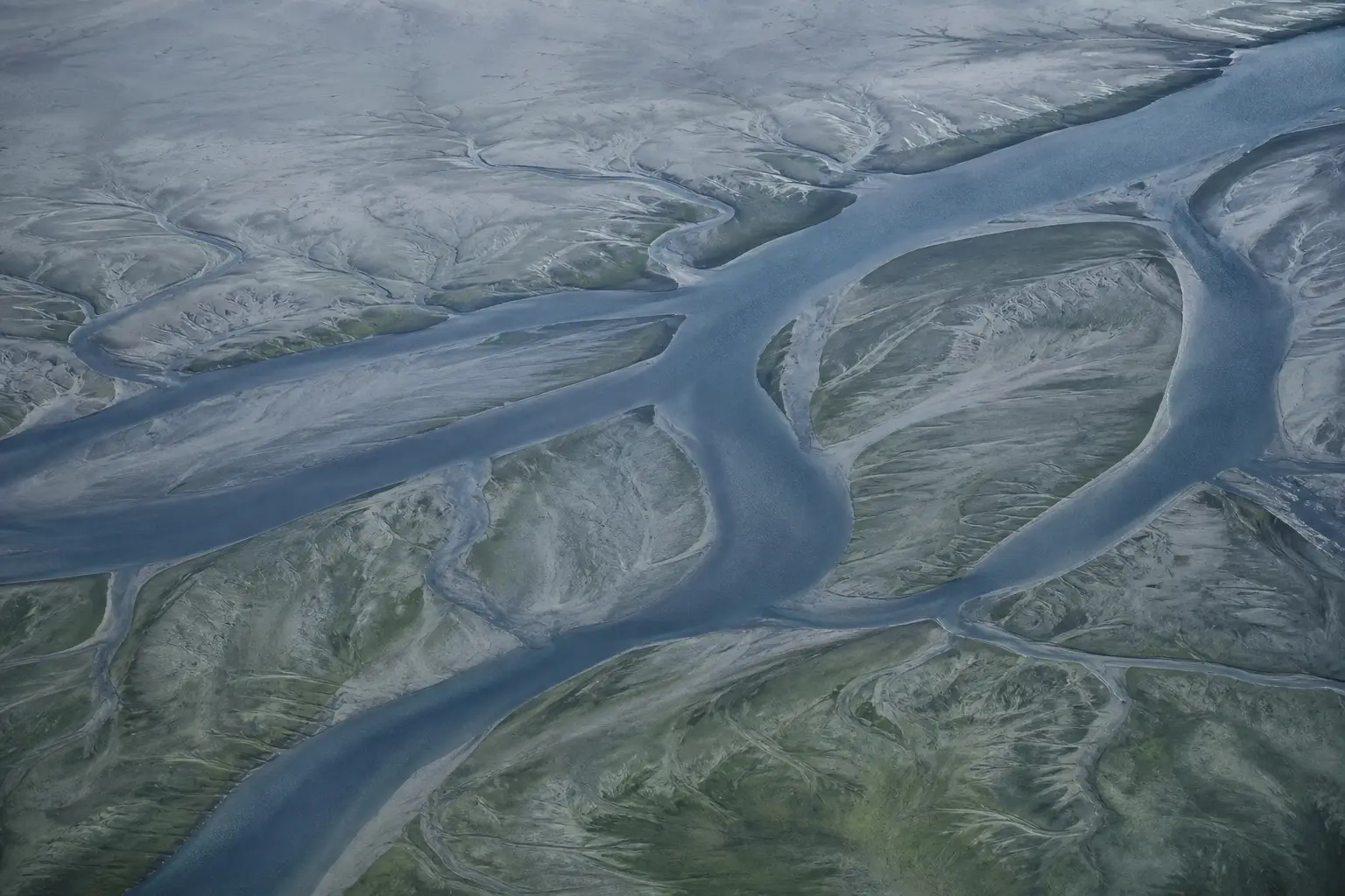An estuary at low tide with channels cut through mud