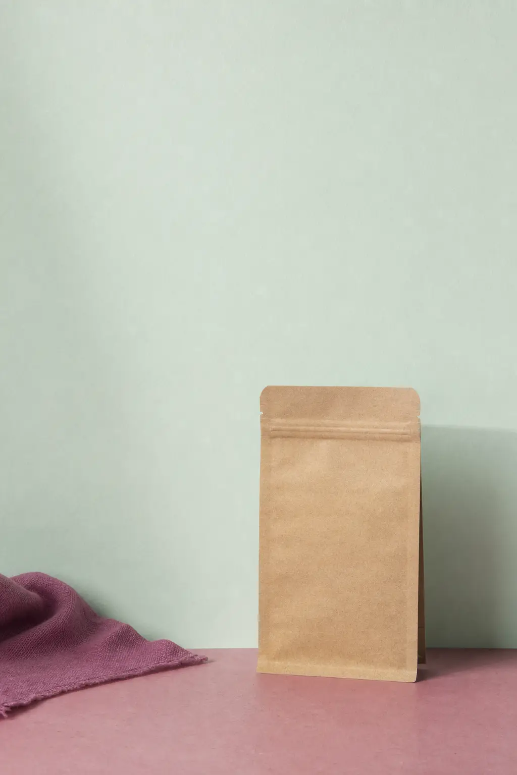A plain paper seed packet standing against a mint wall