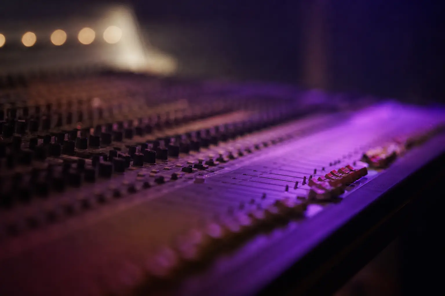 A mixing desk in a dim studio with violet light